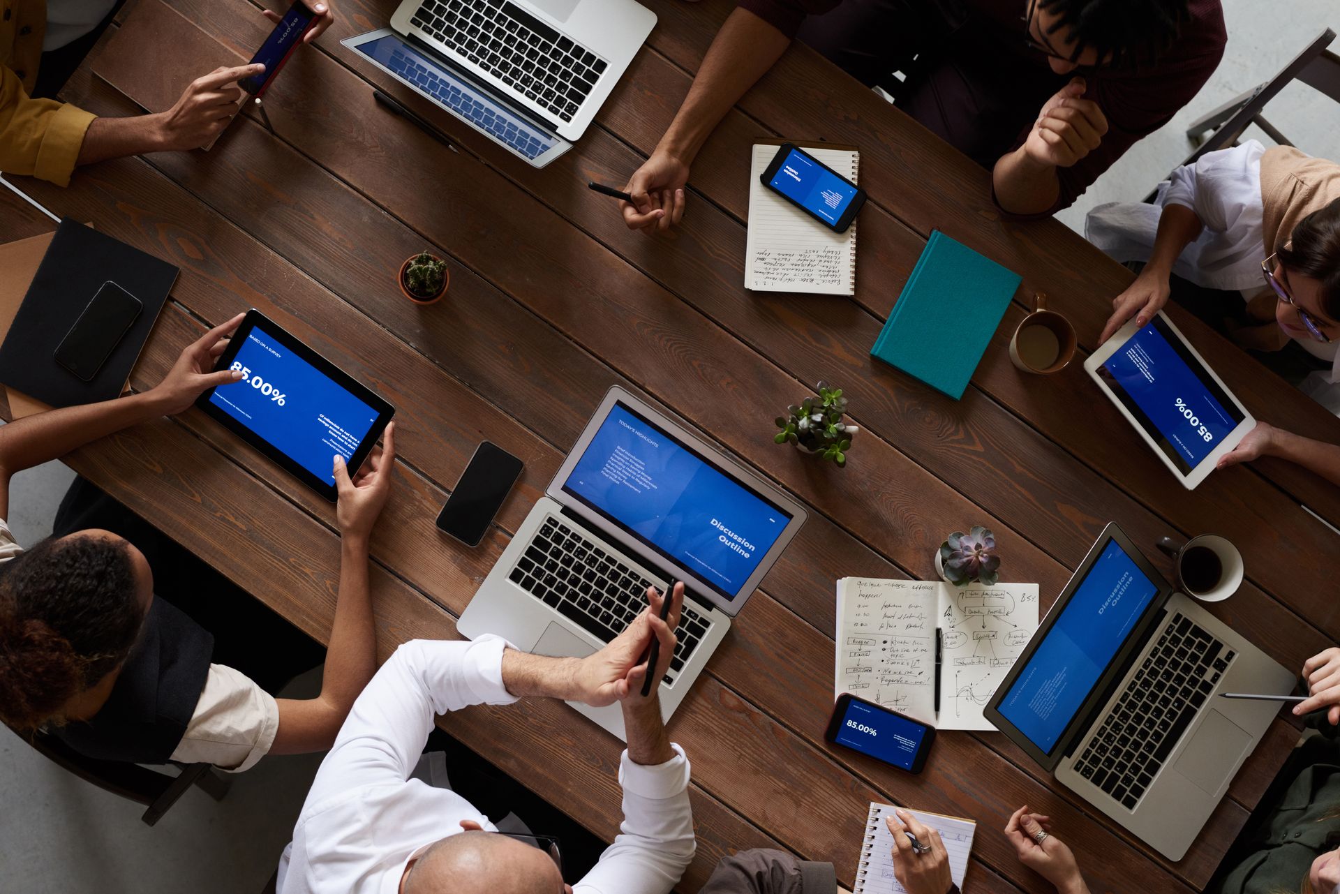 Team arbeitet gemeinsam mit Laptops und Tablets an einem Tisch